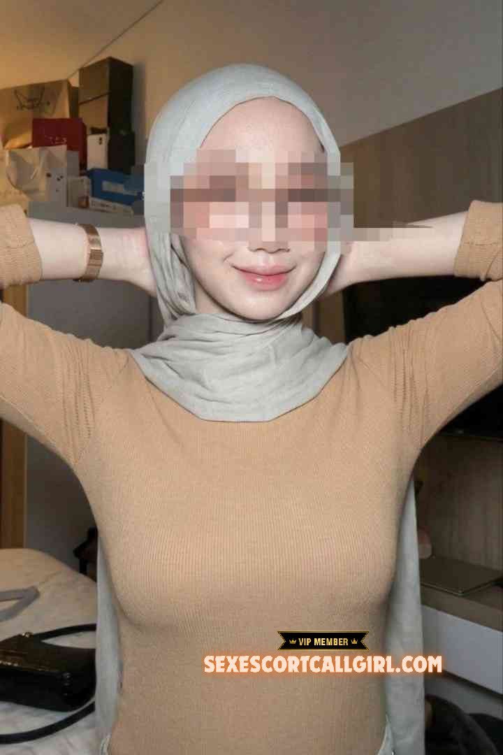 KL Escort Girl Slim Malay woman Kesya wearing a hijab and tan top, posing indoors. Sex Escort Malaysia Girl Service